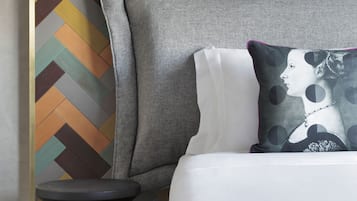 A modern bedroom with a herringbone-patterned headboard, a black side table, and a decorative pillow.