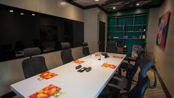 A conference room with a long table, chairs, and a green shelving unit.