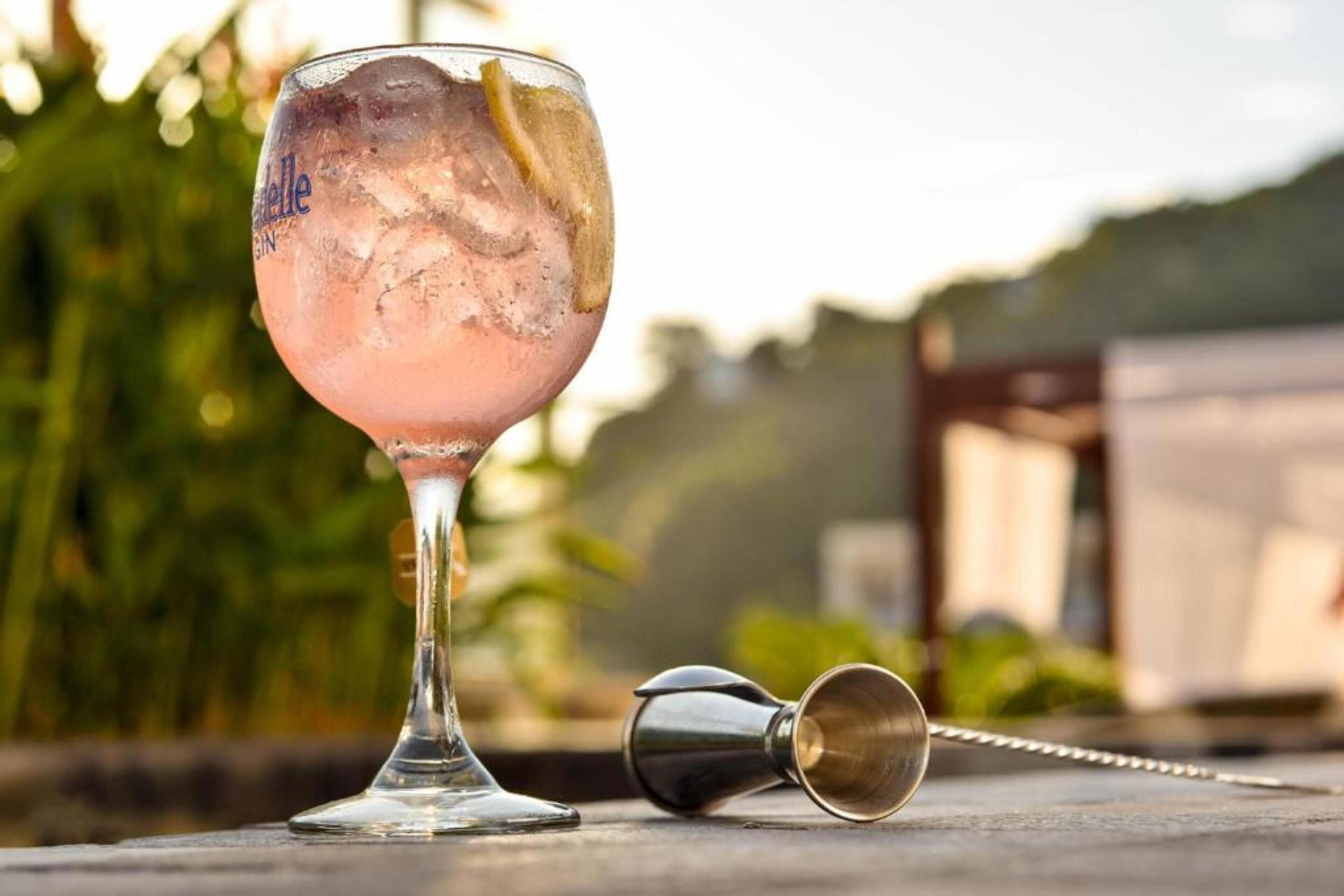 A cocktail glass with ice and a lemon slice on a table.