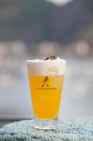 A tall glass of beer with a frothy head, labeled "The Johnnie Walker," on a blue textured surface.