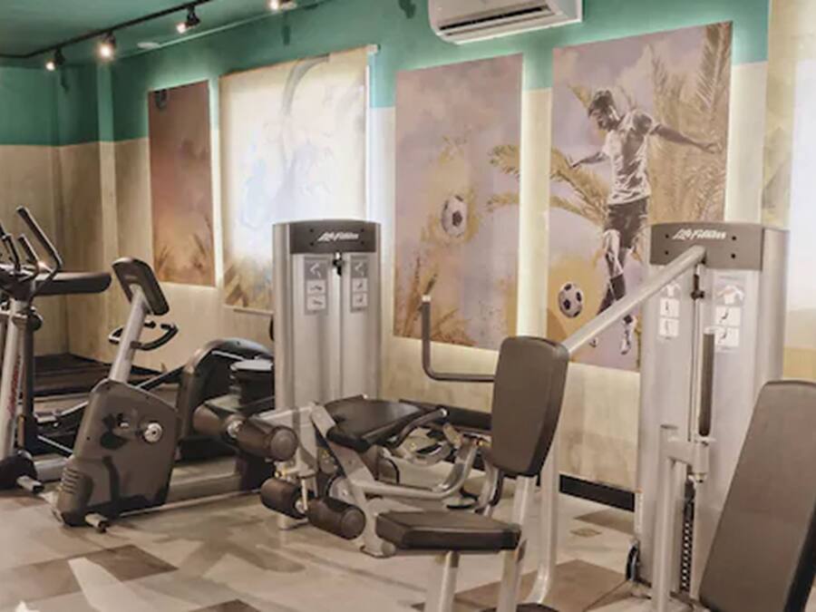 Ein Fitnessstudio mit verschiedenen Trainingsgeräten, darunter Laufbändern und Gewichtecken, sowie einem Wandgemälde.