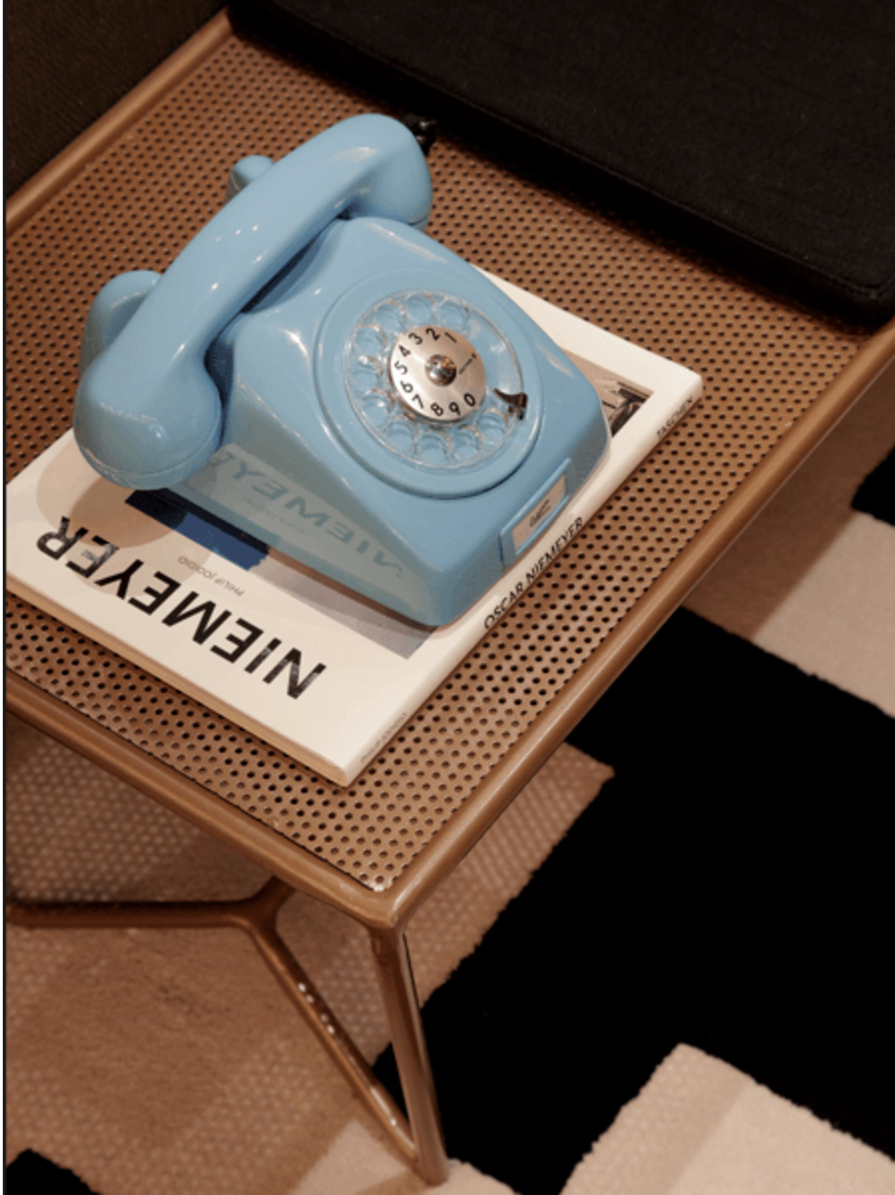 Ein blaues, altes Telefon auf einer weißen Basis, mit dem Schriftzug 'NINEME'.