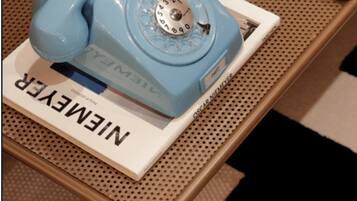 Ein blaues, altes Telefon auf einer weißen Basis, mit dem Schriftzug 'NINEME'.