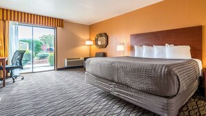 Habitación de hotel con una cama grande, un escritorio, una silla, una ventana con cortinas y un reloj en la pared.