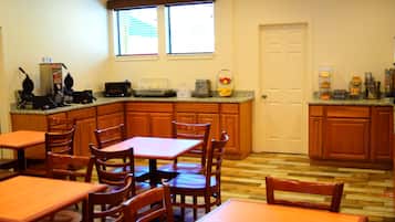 A kitchen with wooden cabinets, a microwave, and a window with blinds.