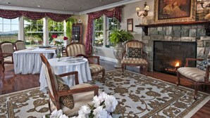 Une salle à manger avec une cheminée, des tables et des chaises, et une vue sur l’extérieur.