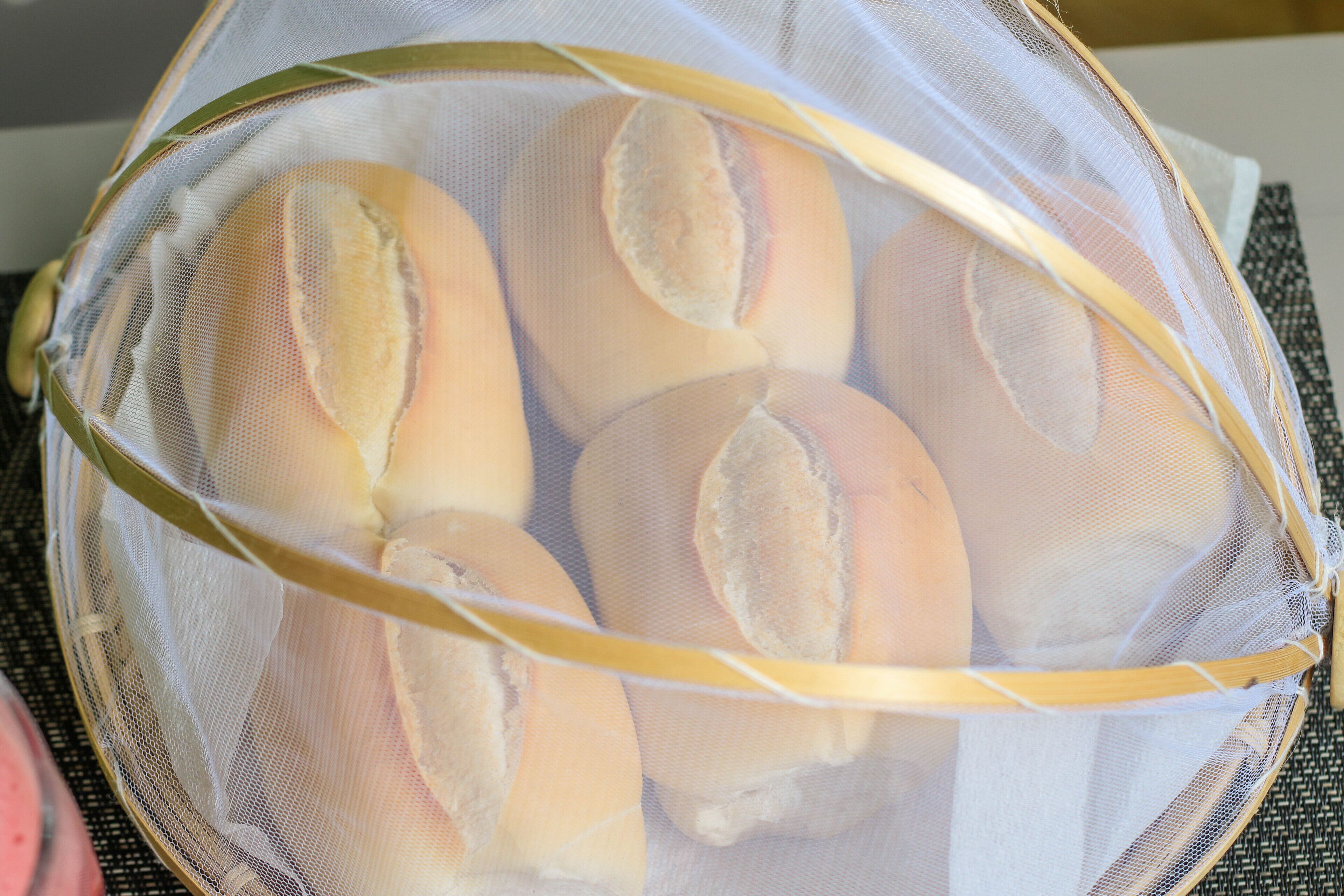 A mesh basket containing several bread rolls.
