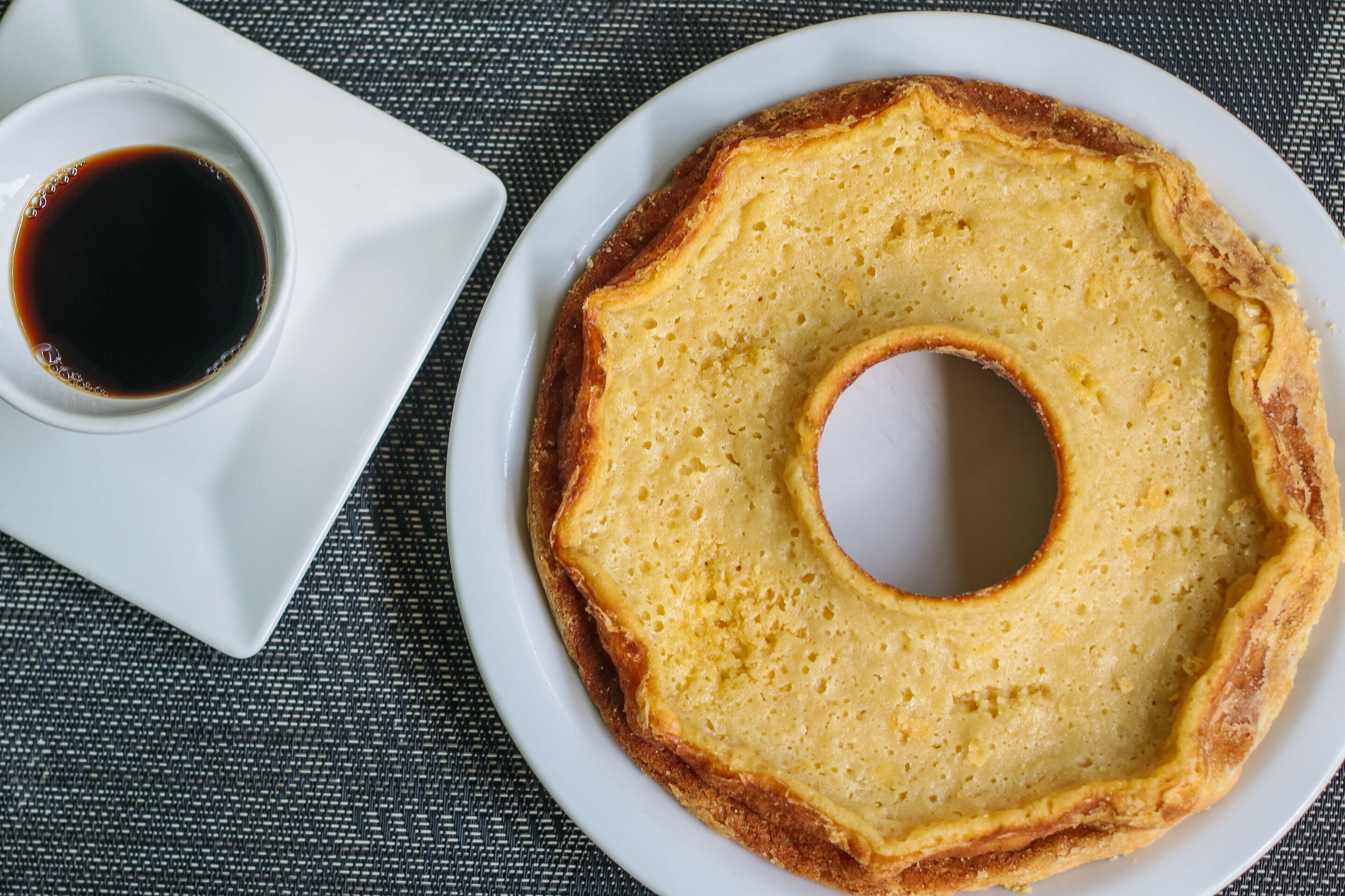 A plate with a ring-shaped food item and a small bowl of sauce.
