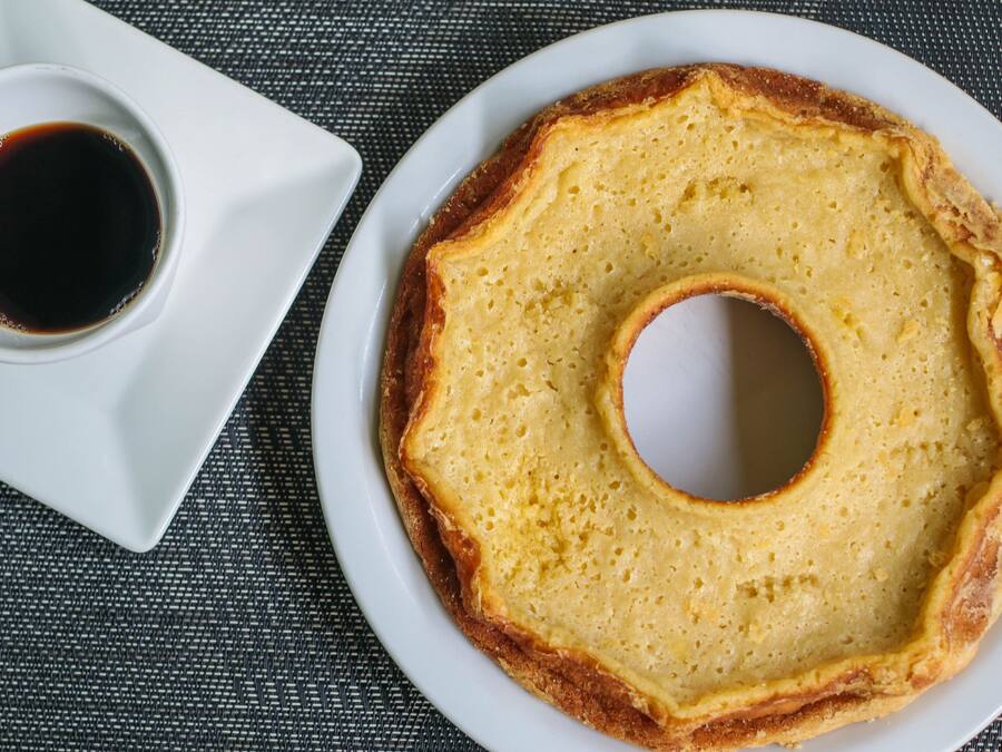 A plate with a ring-shaped food item and a small bowl of sauce.