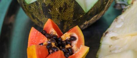 A fruit platter with sliced papaya, pineapple, and a whole melon.