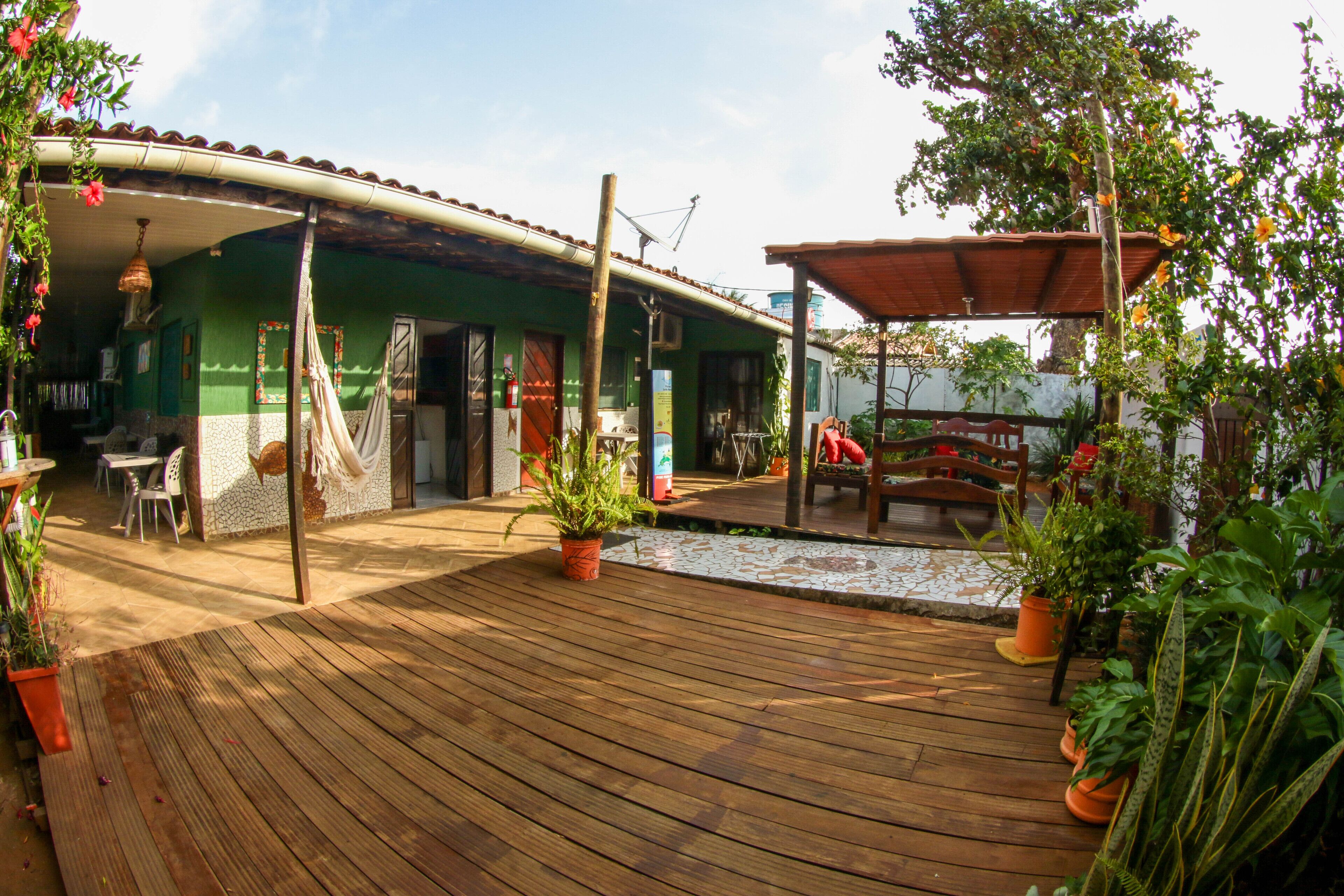 A wooden deck with potted plants, a hammock, and outdoor seating.