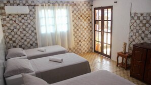A hotel room with two beds, a wooden dresser, and a window with curtains. - Pousada Leão Marinho (Fernando de Noronha)