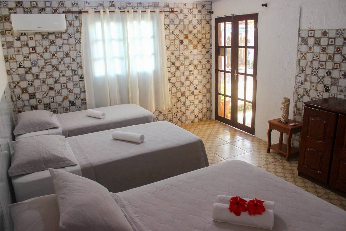 Une chambre d’hôtel avec deux lits, une commode en bois et une fenêtre avec des rideaux.