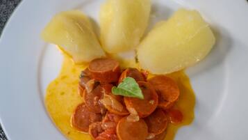 A plate with sliced sausage and boiled potatoes.