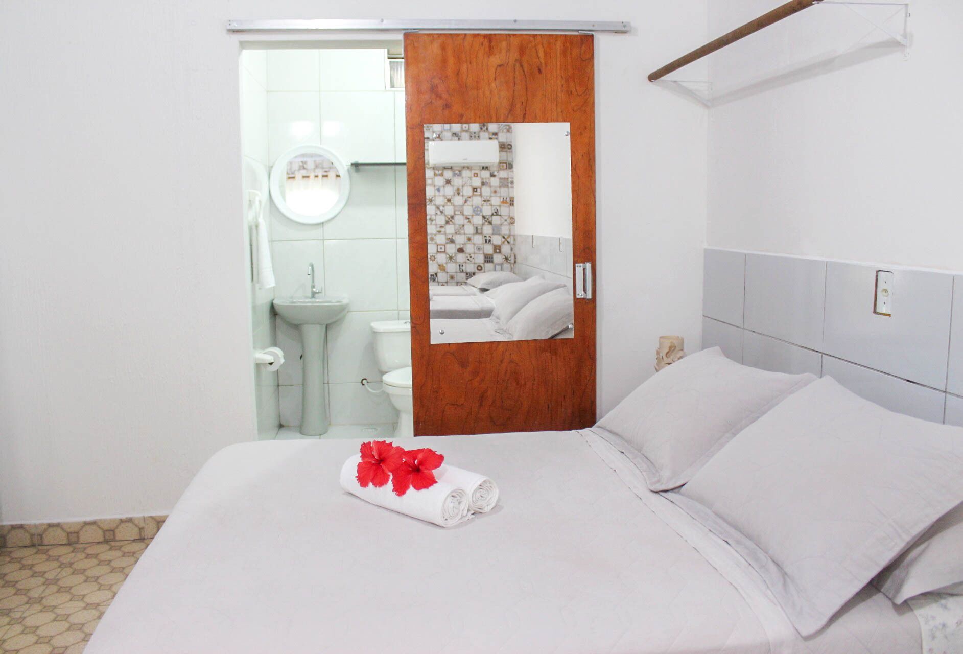 A hotel room with a bed, a bathroom visible through an open door, and a wooden door frame.