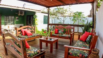 Une terrasse en bois dotée d’un espace salon couvert, comprenant deux canapés et une table.