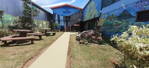 Une auberge de jeunesse appelée « Hostel La Suerte », dotée d’un espace extérieur avec des sièges, d’un sentier et d’une fresque murale.