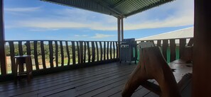 Une terrasse en bois avec une rambarde, un barbecue et une vue sur un paysage verdoyant.