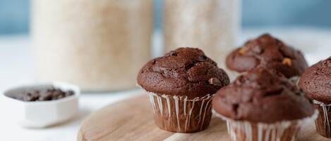 Een houten tafel met verschillende chocolademuffins in bakpapier.