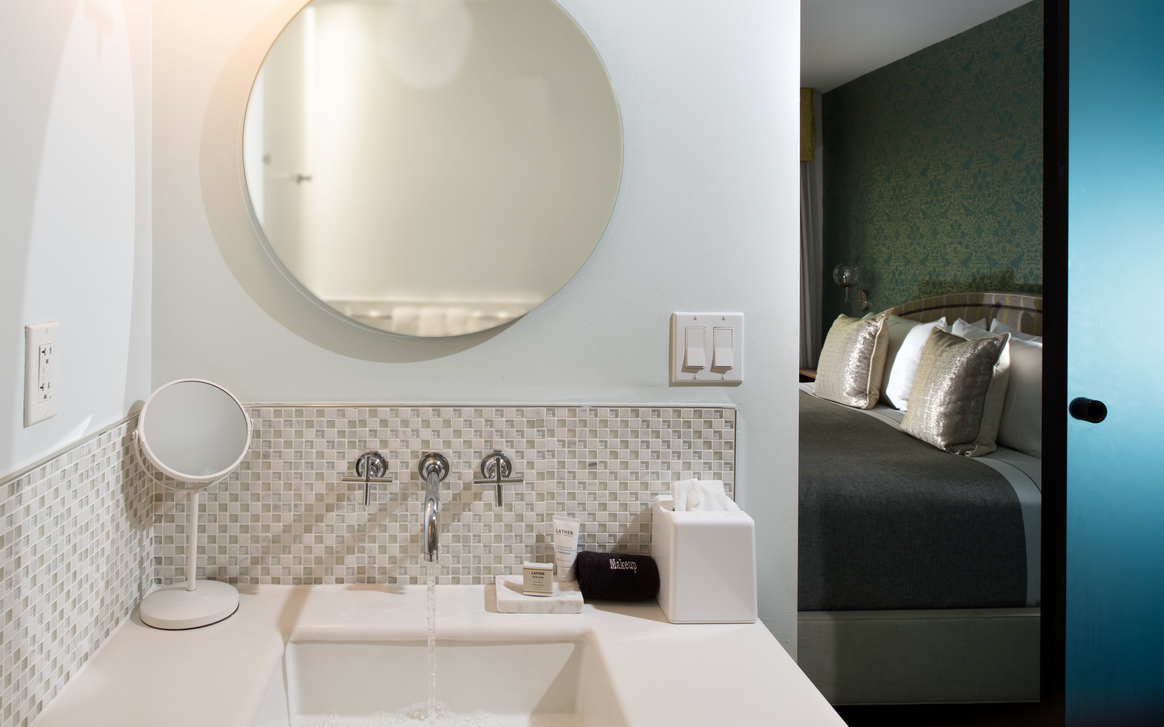 A bathroom with a sink, mirror, and toiletries.