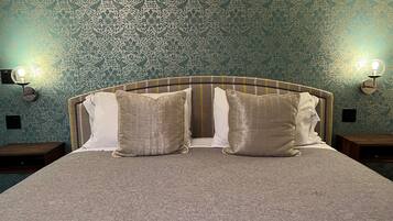 A neatly made bed with a headboard, two bedside tables, and wall sconces.