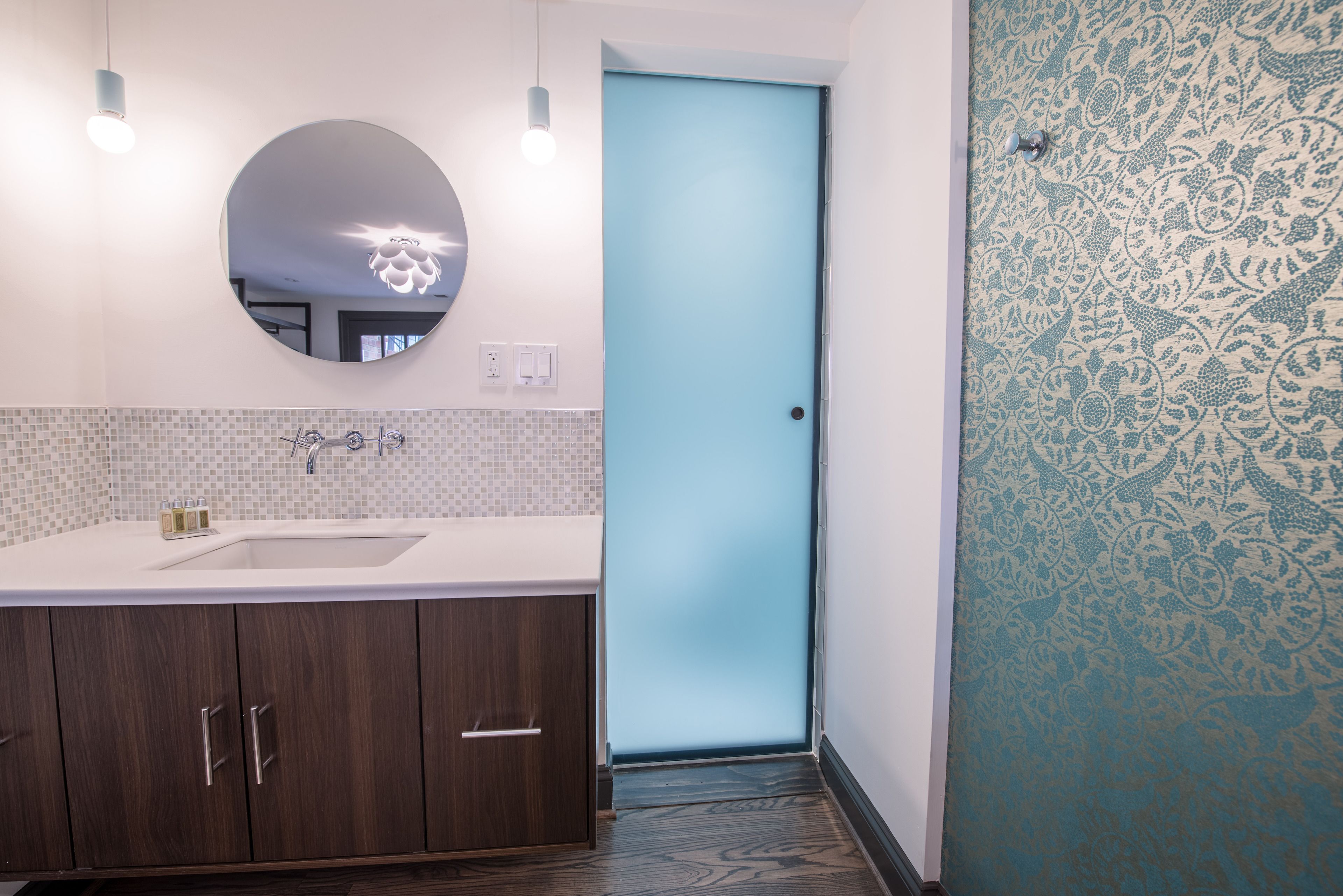 Un bagno con uno specchio grande, un lavandino e una porta con un pannello blu.