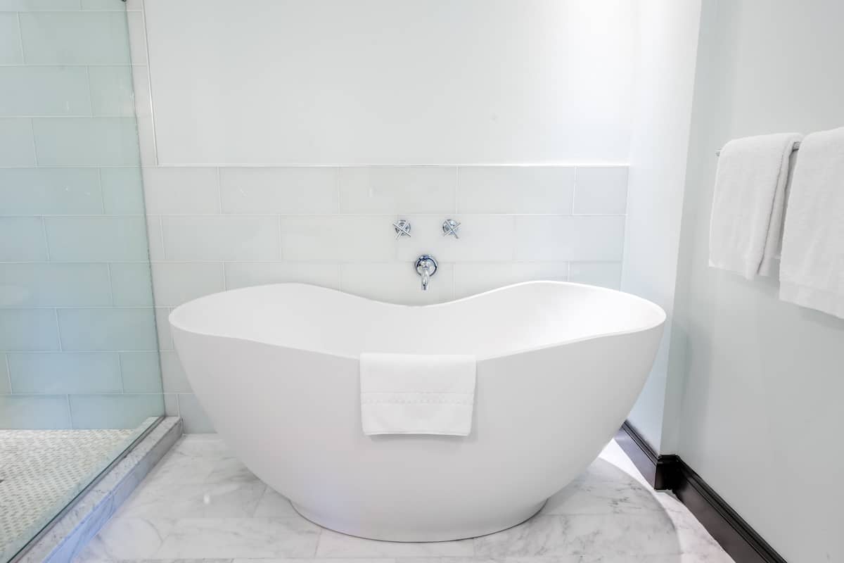 Un baño moderno con una bañera independiente, azulejos blancos y una cabina de ducha de vidrio.
