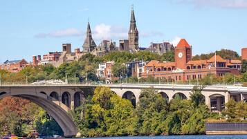 A bridge with arches spanning a river, with buildings and a clock tower in the background.