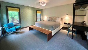 A modern bedroom with a bed, bedside table, chair, and a desk with a chair. - The Poppy Georgetown (Washington)
