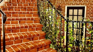 A brick staircase with a metal railing, leading to a door with a window above it. - The Poppy Georgetown (Washington)