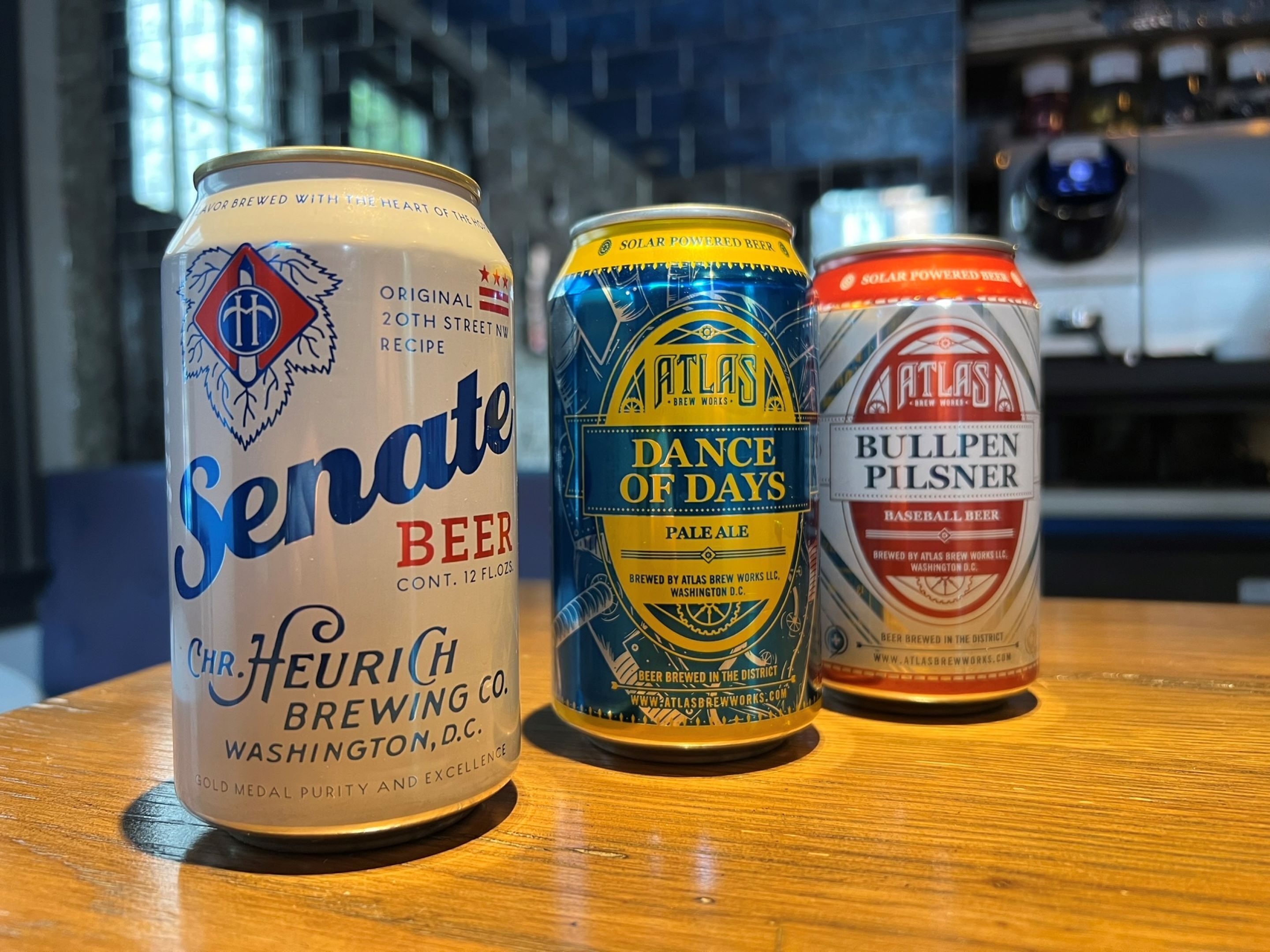 Three cans of beer on a wooden table.