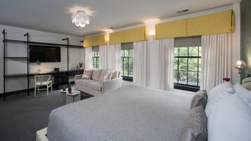 Una habitación de hotel moderna con una cama grande, un escritorio, un sofá y un televisor.