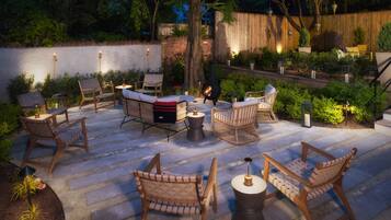 An outdoor patio with wicker furniture, a fire pit, and decorative lanterns.