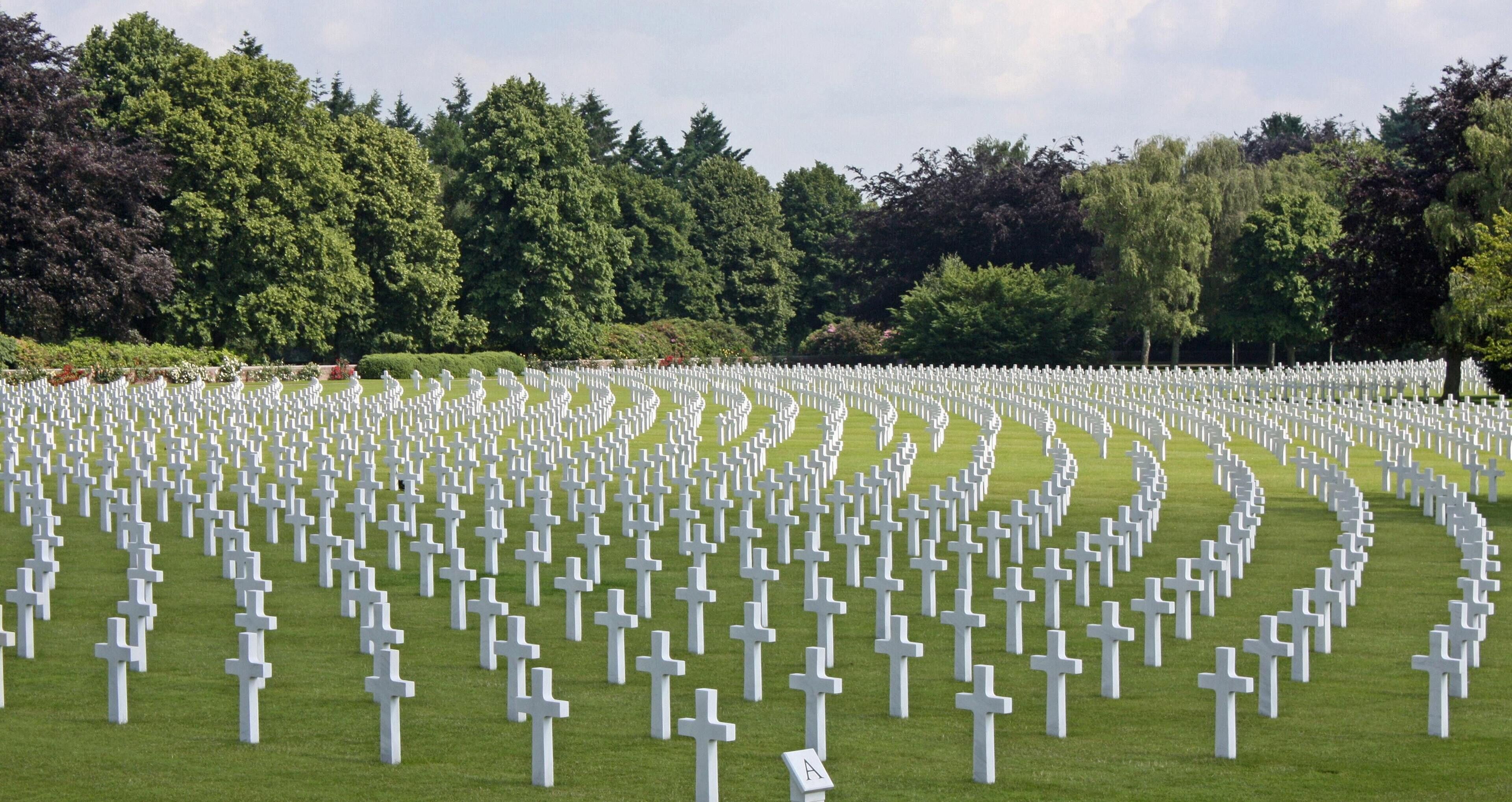 A cemetery with numerous white crosses arranged in rows.
