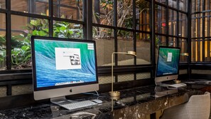 Two Apple iMac computers on a marble counter with a keyboard and mouse, in front of a window with plants. - Heaven on Washington Furnished Apartments (Washington)
