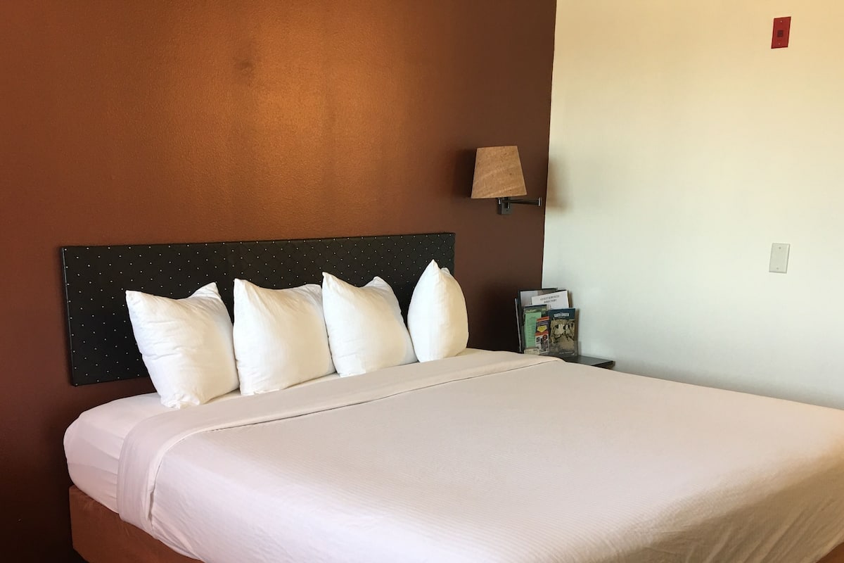 A neatly made bed with white linens in a hotel room.