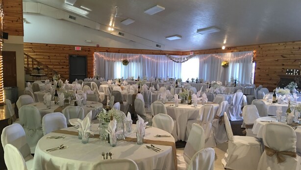 A banquet hall with round tables, white tablecloths, and chairs covered in white fabric. - The Galley Hotel Bar and Grill (Webster)