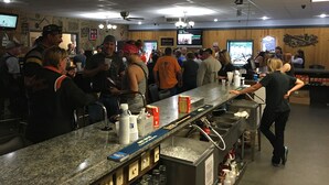 A busy bar area with a granite countertop, ice bucket, and stacked cups. - The Galley Hotel Bar and Grill (Webster)