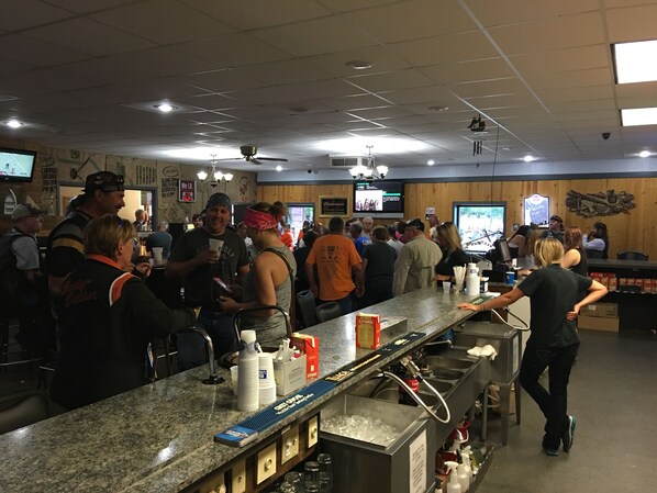 A busy bar area with a granite countertop, ice bucket, and stacked cups.