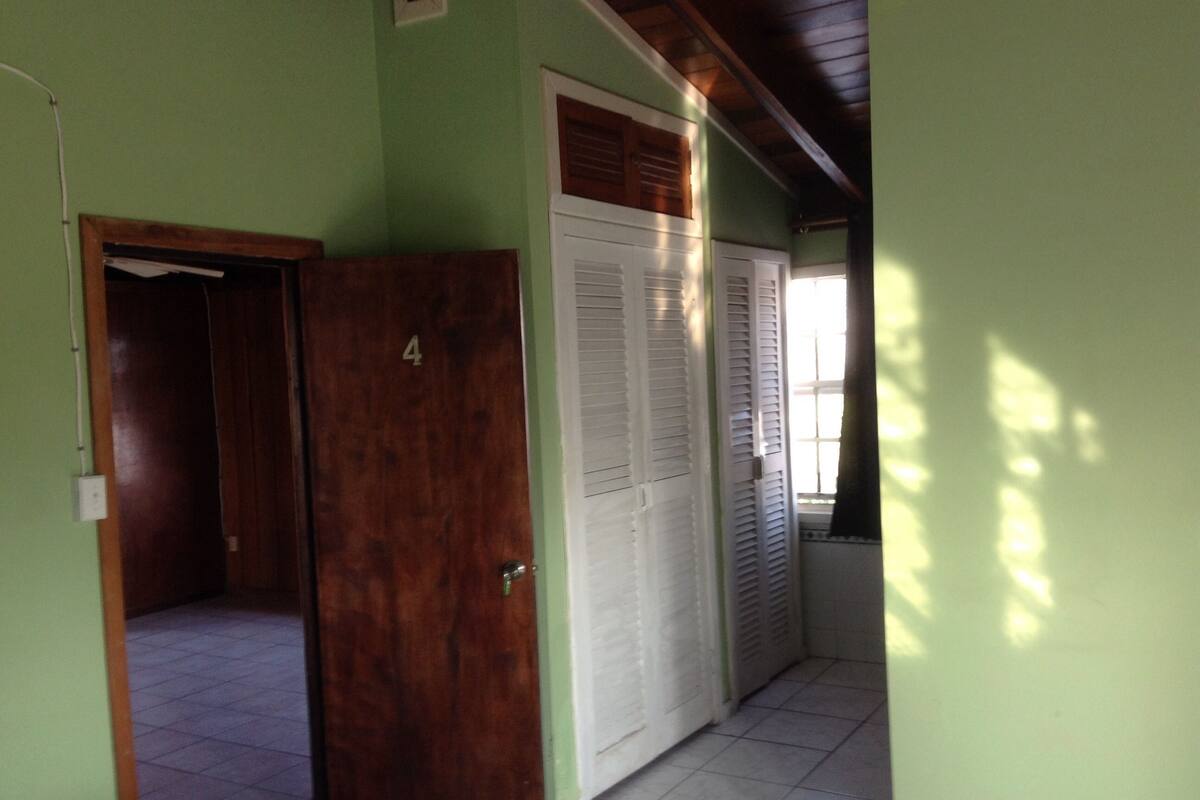 A hallway with a wooden door labeled '4', a white door with louvered shutters, and a tiled floor.
