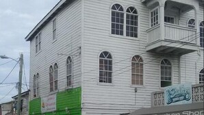 A two-story building with a green storefront and a barber shop on the ground floor.