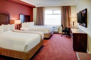A hotel room with two beds, a desk, a TV, and a window with curtains. - Chateau Nova Yellowhead (Edmonton)