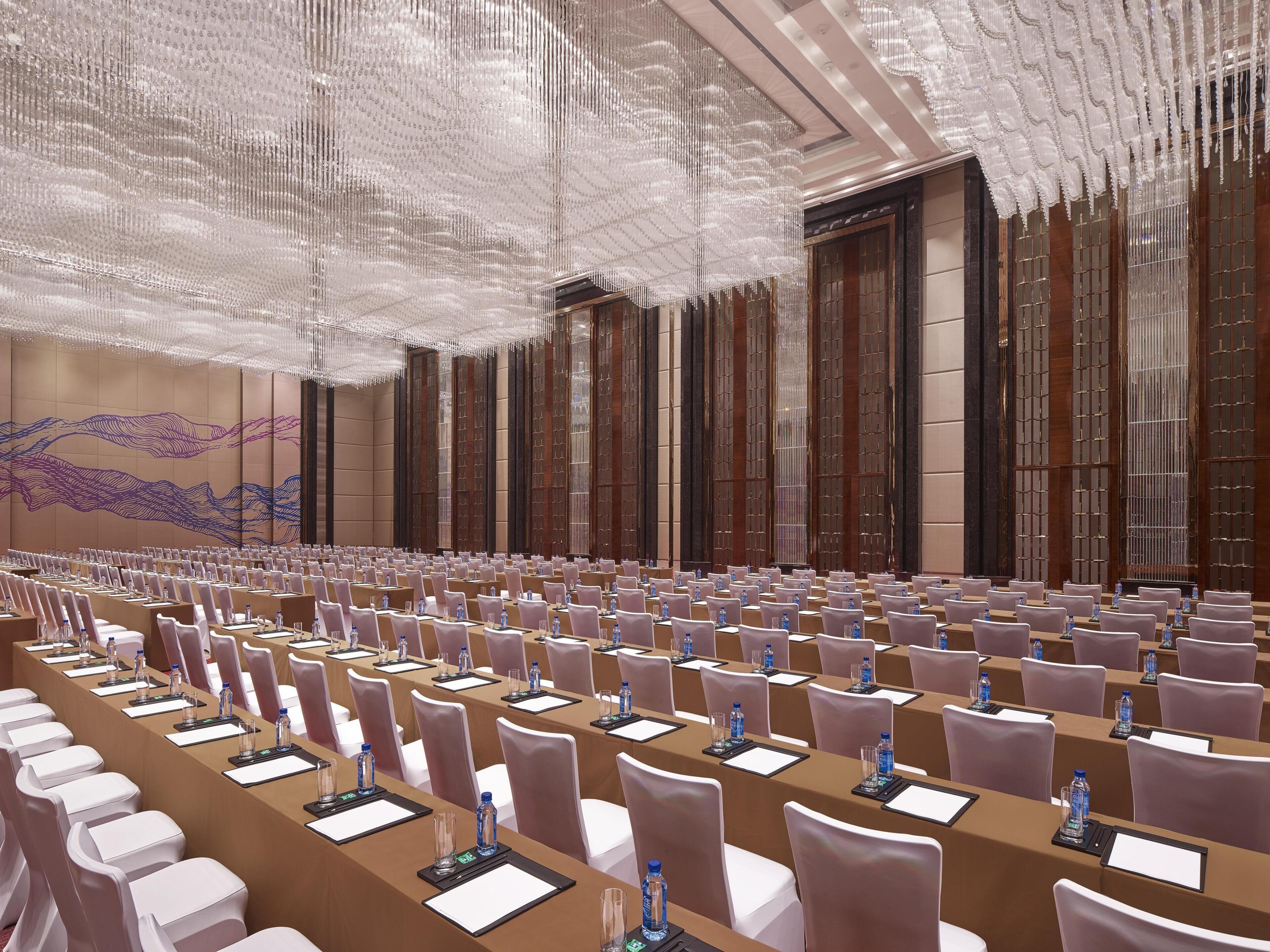 A conference room with rows of tables, chairs, and water bottles.