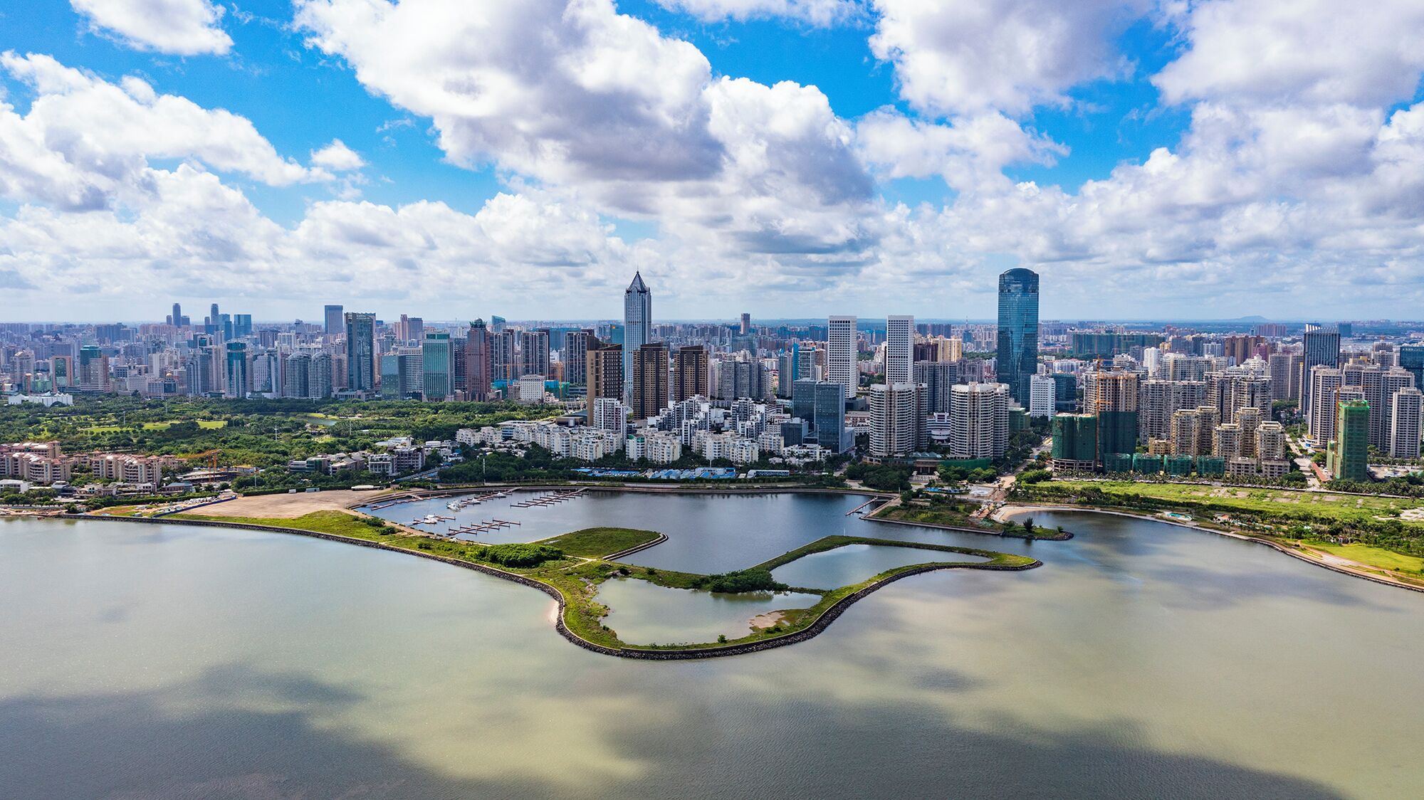 A cityscape with high-rise buildings, a central park with a lake, and a clear sky.