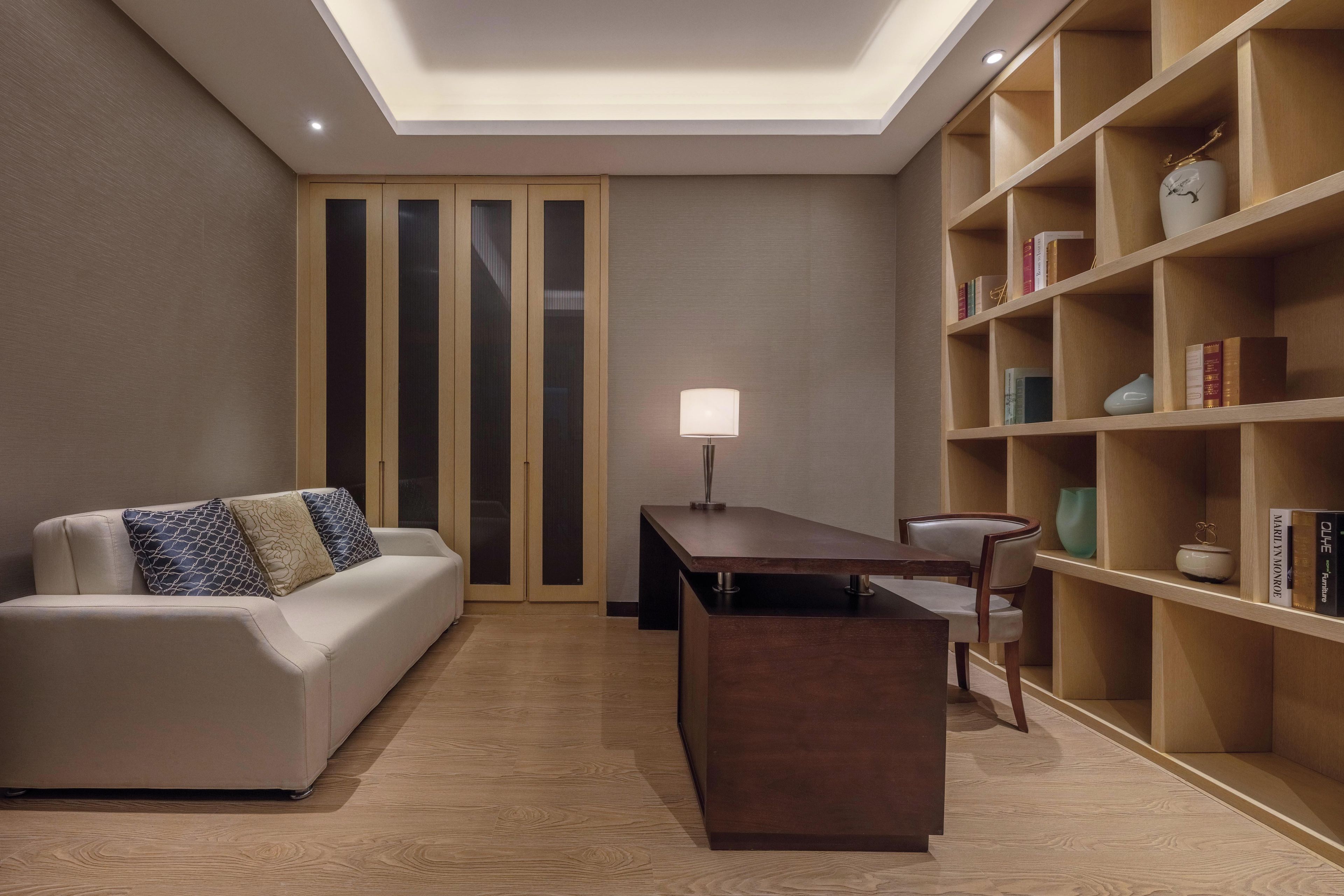 Uma sala de estar moderna com sofá, mesa de centro, estante e escrivaninha com abajur.