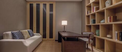 Uma sala de estar moderna com sofá, mesa de centro, estante e escrivaninha com abajur.