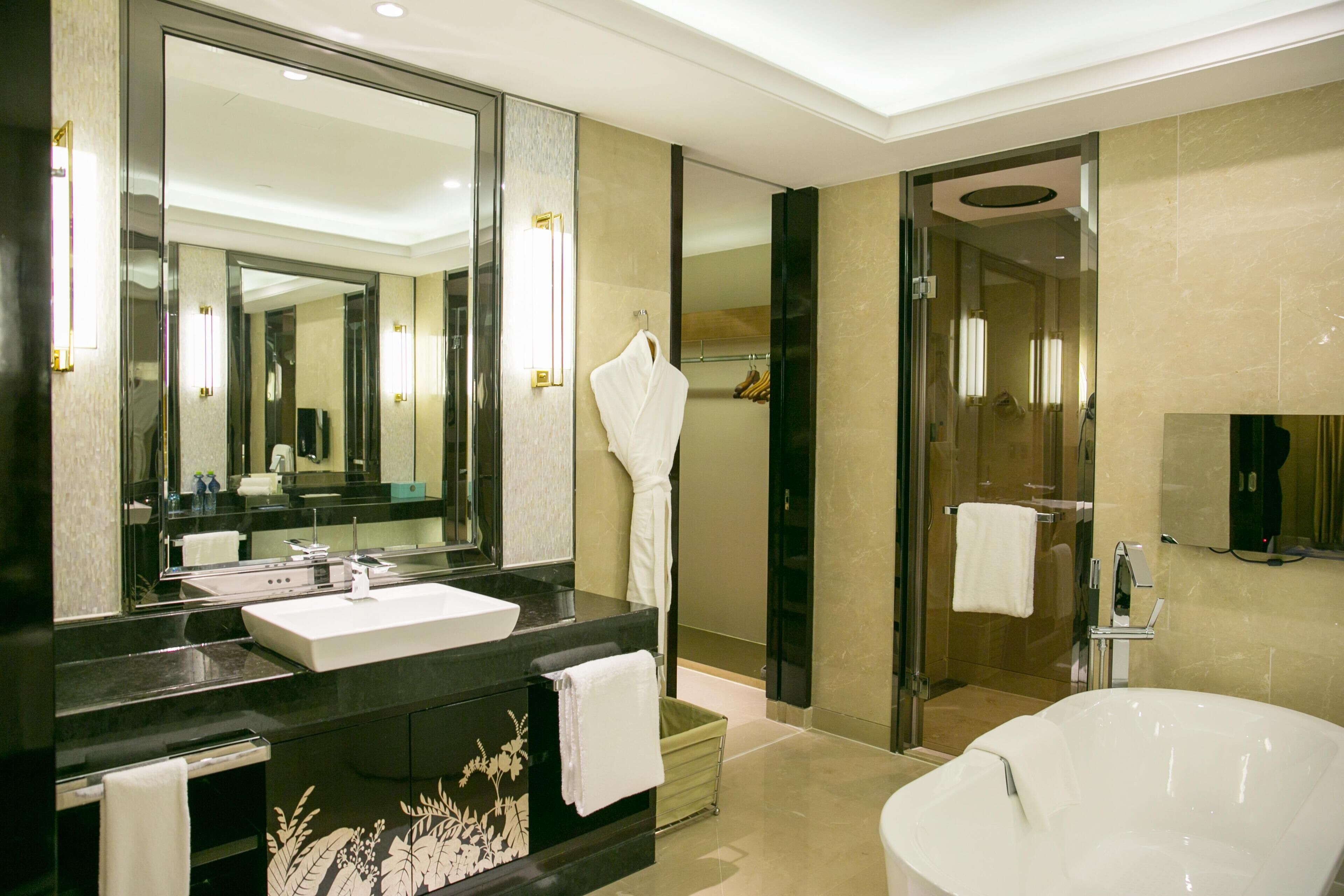 Un baño moderno con un espejo grande, un lavabo blanco, una bañera y una zona de ducha.