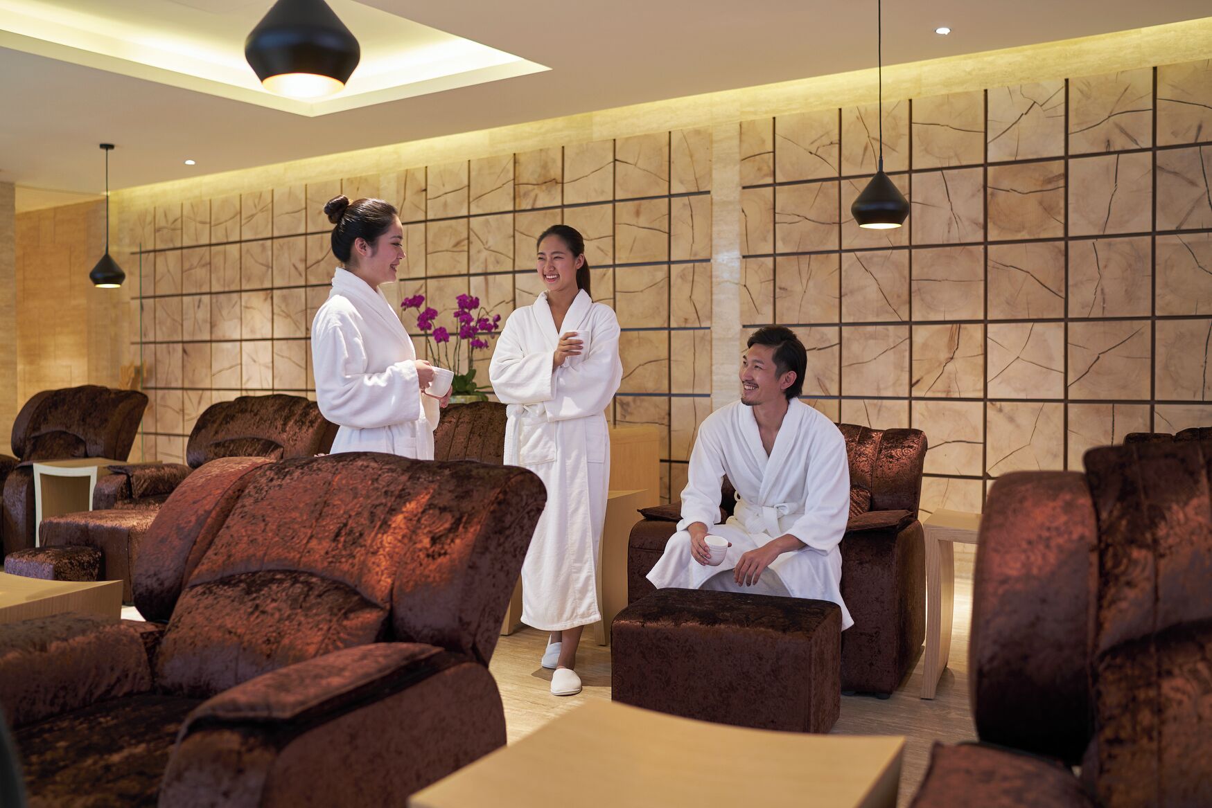 Un área de spa con sillones de masaje, una recepción y una pared con diseño texturizado.