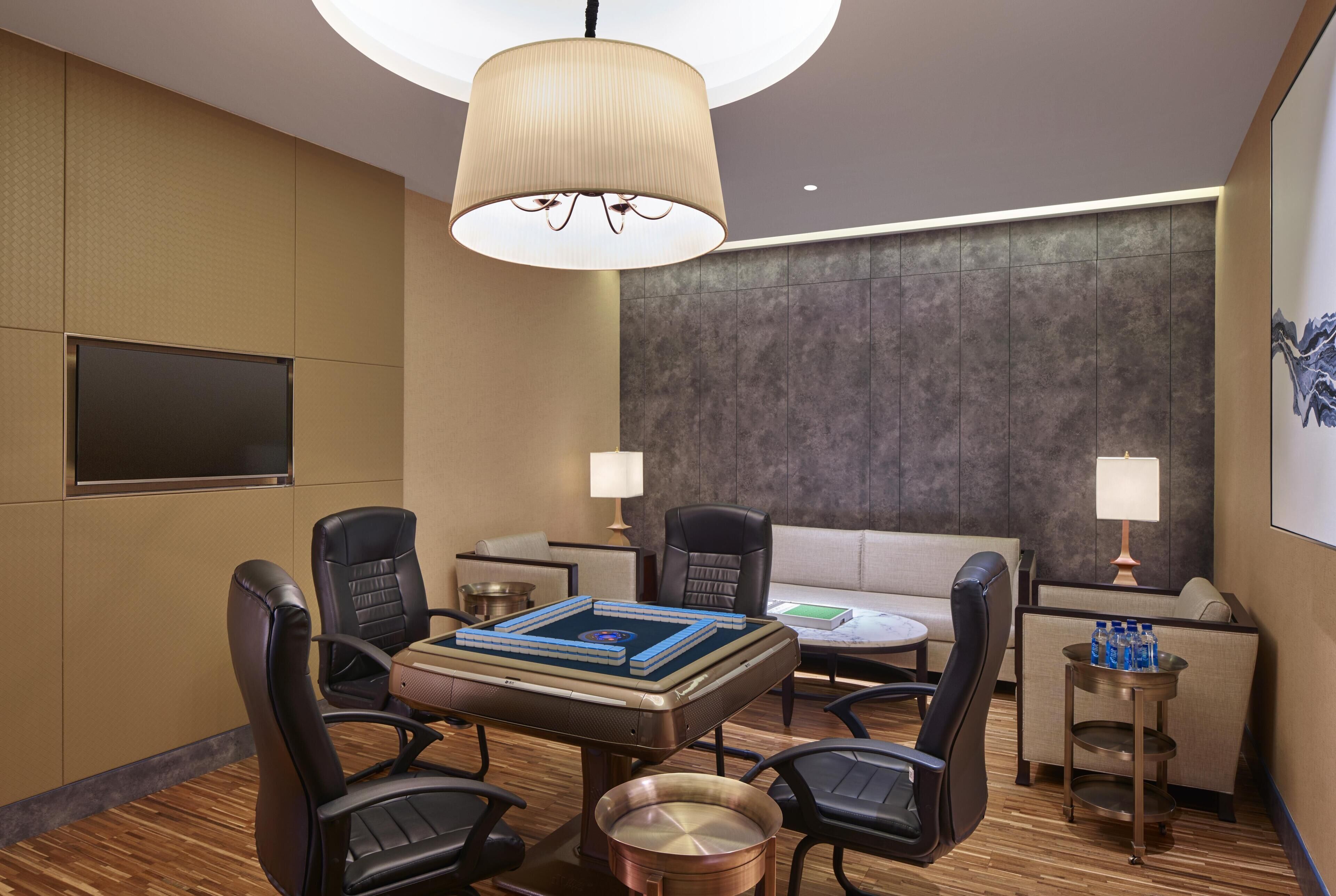 A modern conference room with a round table, four chairs, a sofa, two lamps, and a flat-screen TV.
