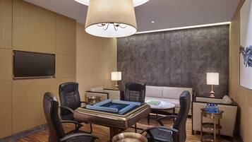 A modern conference room with a round table, four chairs, a sofa, two lamps, and a flat-screen TV.